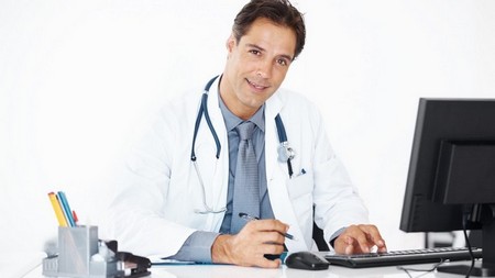 Portrait of handsome doctor using computer in office